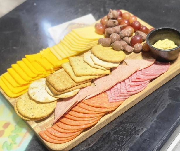 Large charcuterie board with mixed meats, cheeses, fruit, nuts