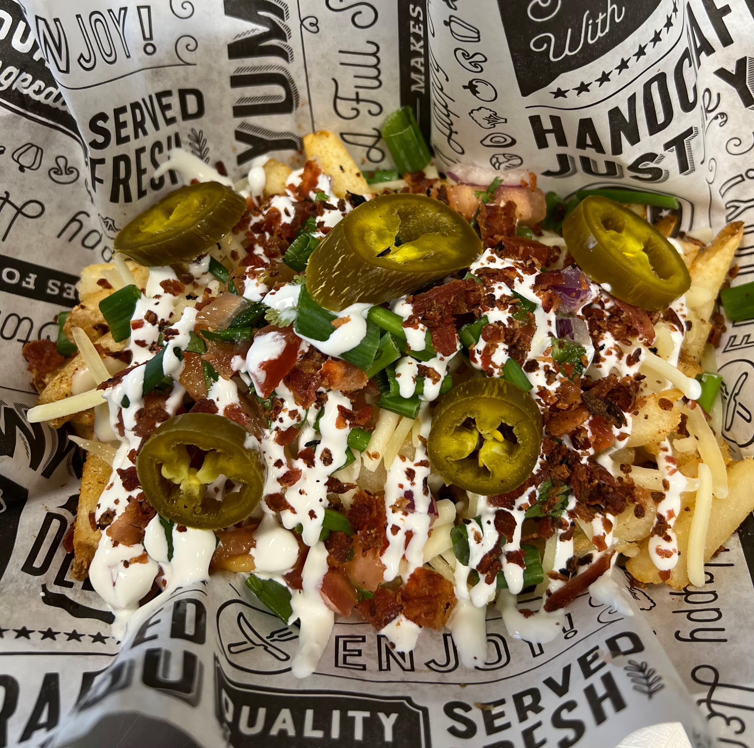 Loaded Seasoned Fries, topped with queso, pico de gallo, pickled jalapenos, green onions, sour cream & bacon