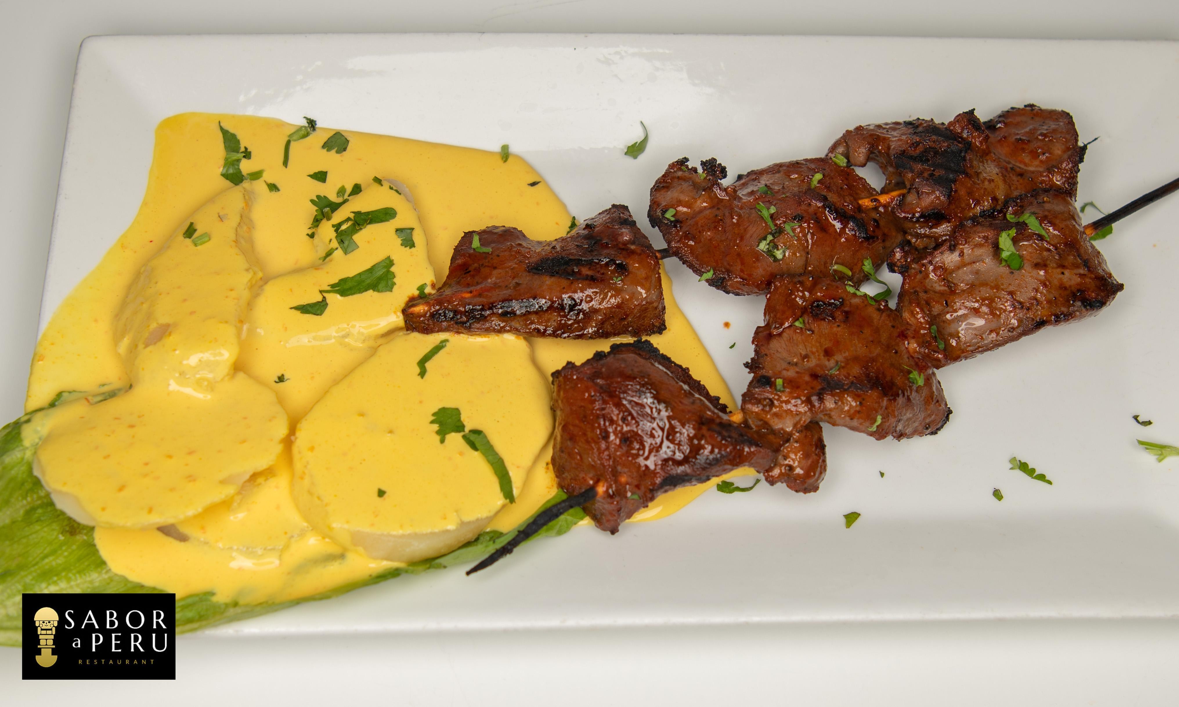ANTICUCHOS CON PAPA A LA HUANCAINA / GRILLED COW HEART SKEWERS & YELLOW SAUCE ON POTATOES